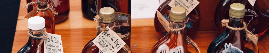 A collection of maple syrup bottles with rustic tags on a wooden table