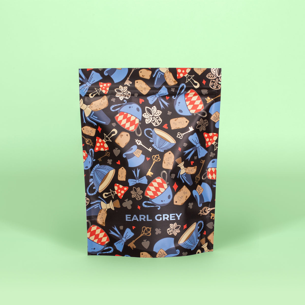 A package of Earl Grey pyramid tea with a pattern of blue and red tea cups, keys, and floral designs on a green background.